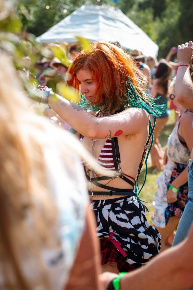 A crowd gathered outdoors at Rewild Festival in Ireland, with a decorated stage and string lights.