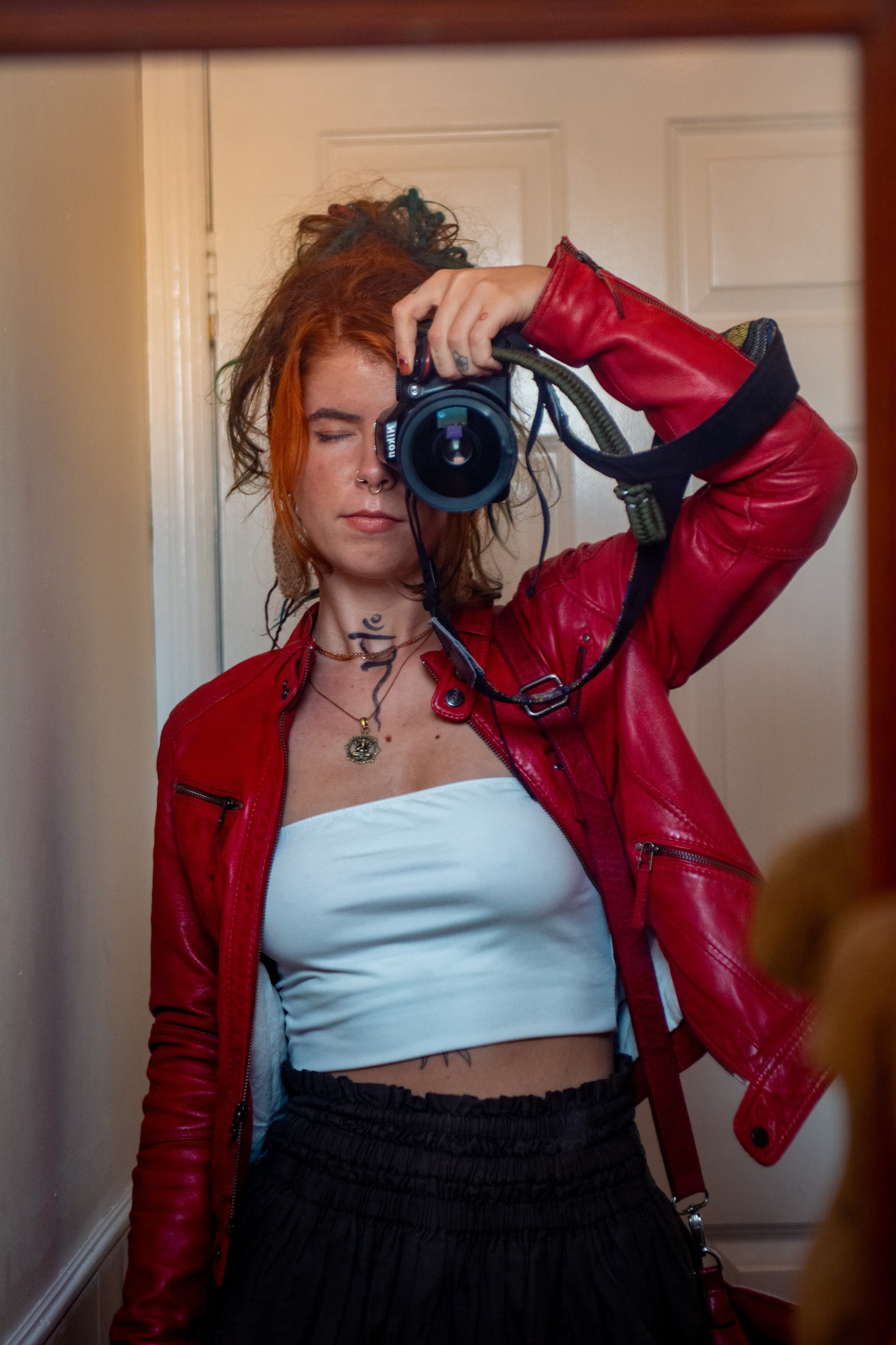 Agota in a red jacket holding a camera to her eye.